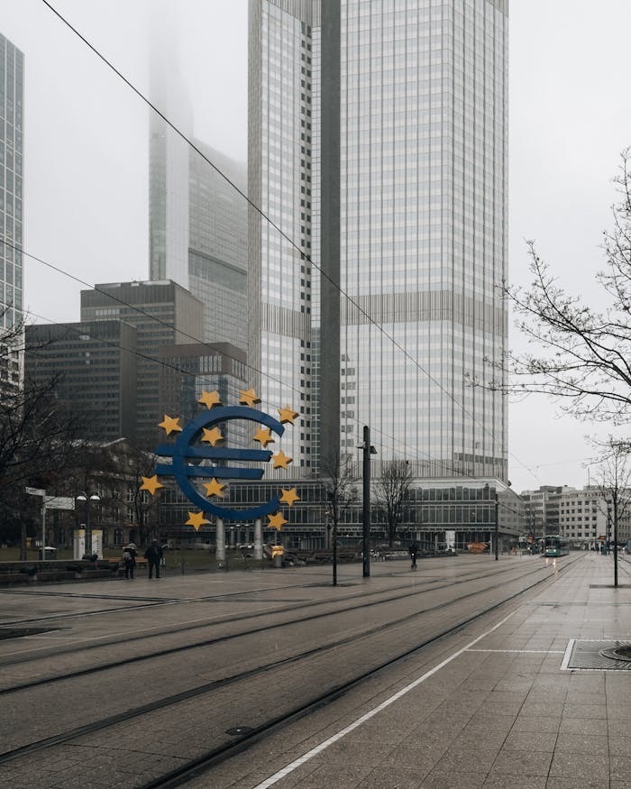 Dramatic view of Frankfurt's Eurotower and skyscrapers amid fog, street and tramway in foreground.