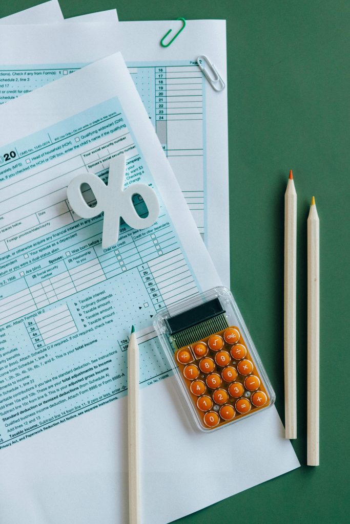 pexels-photo-6863175-6863175 Flat lay of tax documents, calculator, and pencils on green surface.