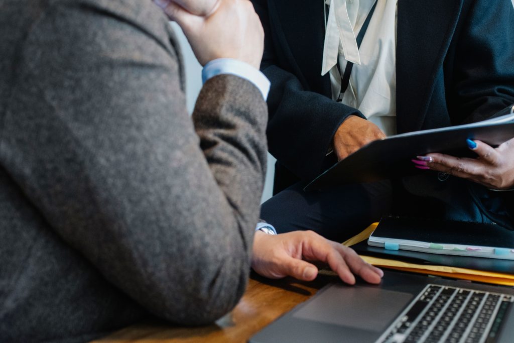 pexels-photo-5668826-5668826 Crop faceless ethnic female entrepreneur in classy suit showing document to anonymous male boss sitting at table with laptop
